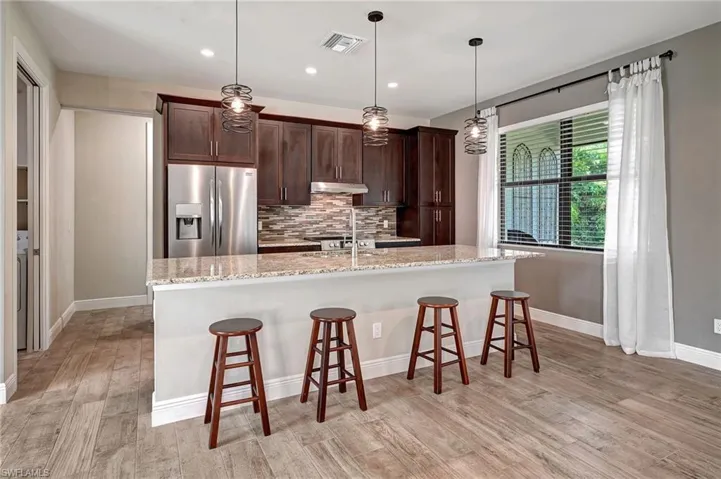 Kitchen featuring light stone countertops, stainless steel appliances, Glass backsplash and pendant lights over the Island.