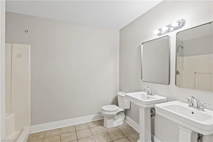 Primary bath featuring twin pedestal sinks and a walk-in shower, combining comfort and functionality.