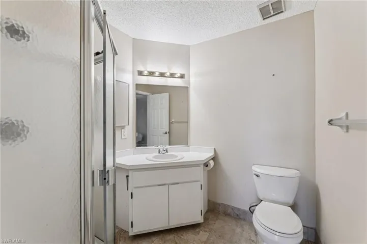 Full bath with vanity, a stall shower, a textured ceiling, and light tile patterned floors