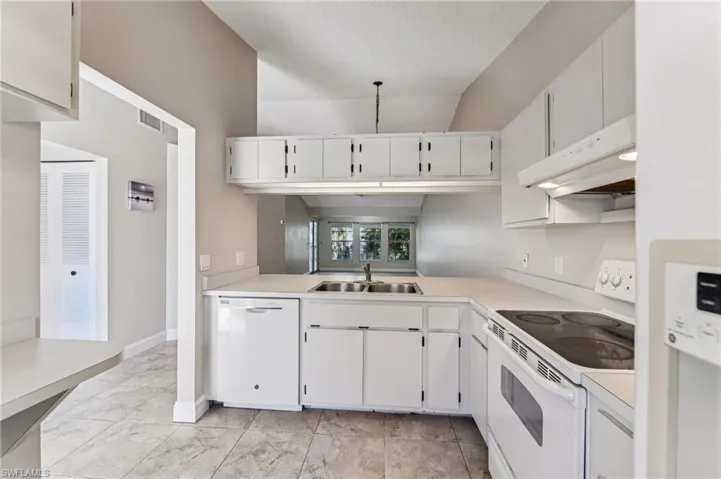 Kitchen featuring white appliances, light countertops, white cabinets, and a textured ceiling
