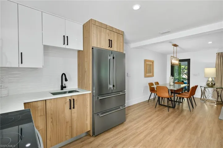 Kitchen with dual tone cabinetry, high end fridge, light wood-type flooring, backsplash, and beam ceiling