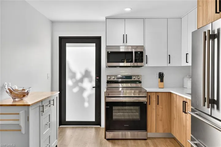 Dual tone kitchen featuring stainless steel appliances, two tone cabinets, light wood-style floors, tasteful backsplash, and modern cabinets