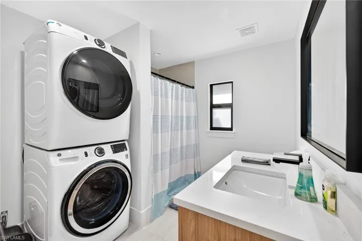Laundry area featuring stacked washing machine and dryer and light tile patterned floors