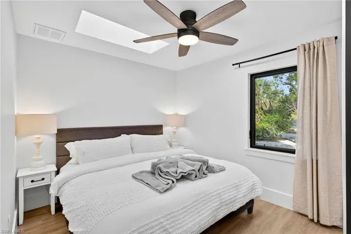 Bedroom with light wood-style flooring, ceiling fan, and a skylight