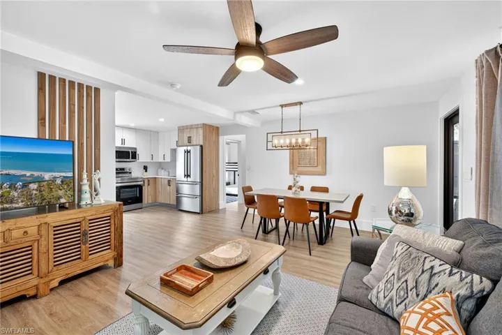 Living room with a ceiling fan, light wood finished floors, and a chandelier
