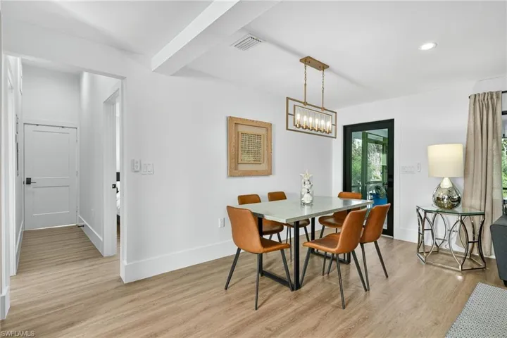 Dining area with light wood-style floors, beamed ceiling, and recessed lighting
