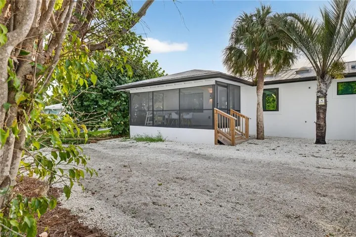 Back of house featuring a sunroom, stucco siding, and a metal roof