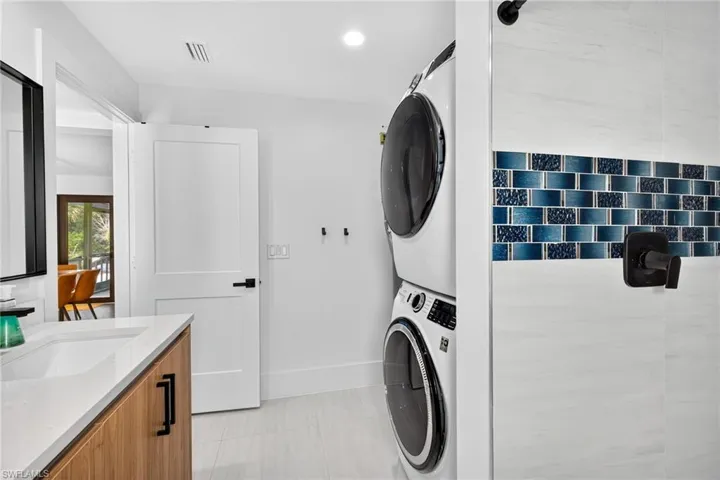 Laundry area featuring stacked washer / dryer, light tile patterned flooring, and recessed lighting