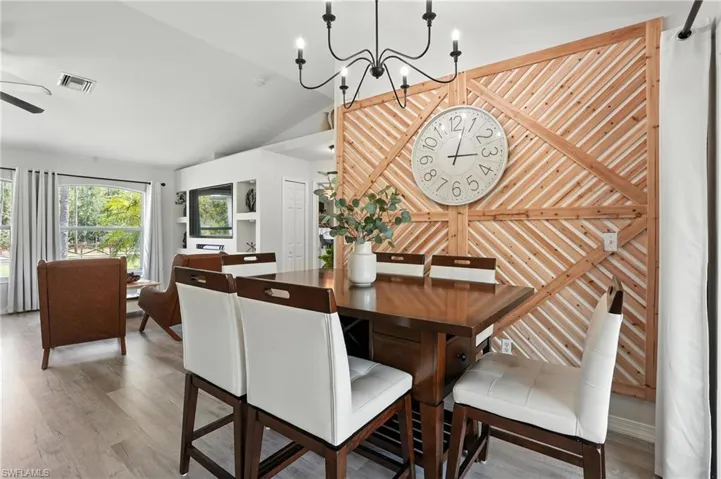 Dining space with vaulted ceiling, a chandelier, wood finished floors, and ceiling fan