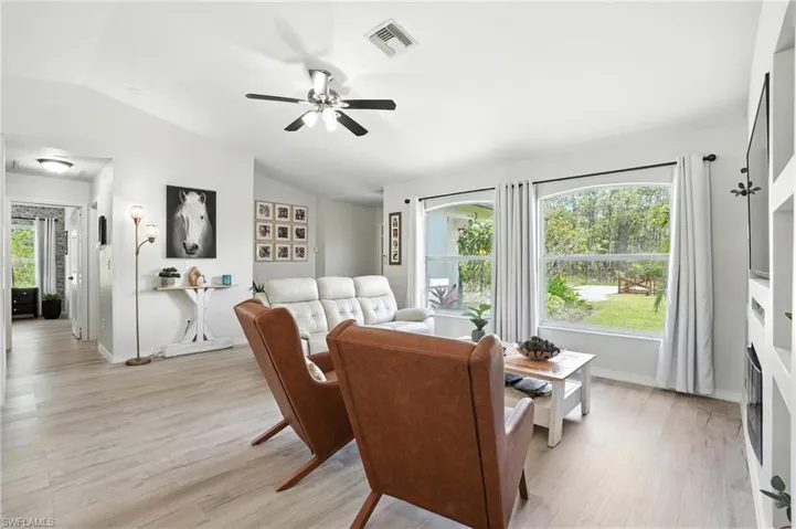 Living room with vaulted ceiling, a ceiling fan, and light wood-type flooring