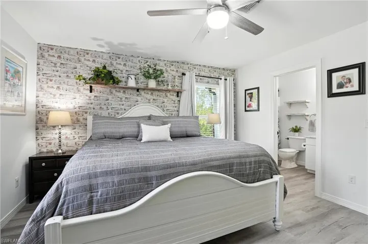 Bedroom with wood finished floors, ensuite bath, and a ceiling fan