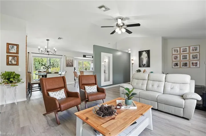 Living area with a chandelier, lofted ceiling, a ceiling fan, and light wood-style floors