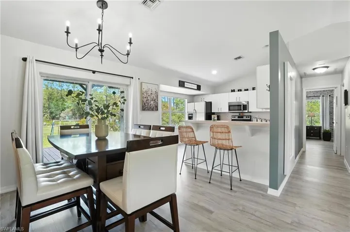 Dining room featuring a chandelier, light wood-style floors, and vaulted ceiling