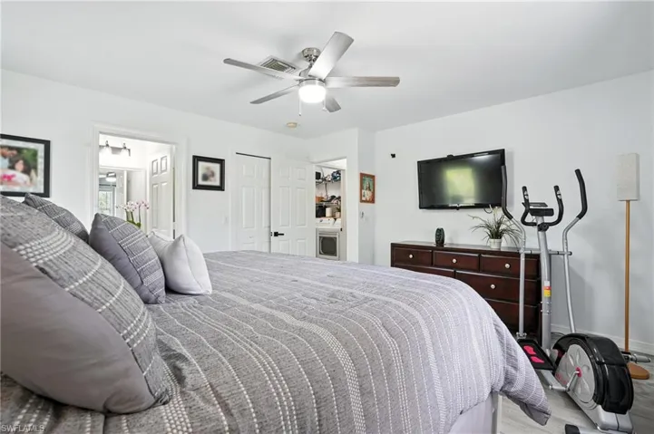 Bedroom featuring ceiling fan, wood finished floors, ensuite bath, and a closet