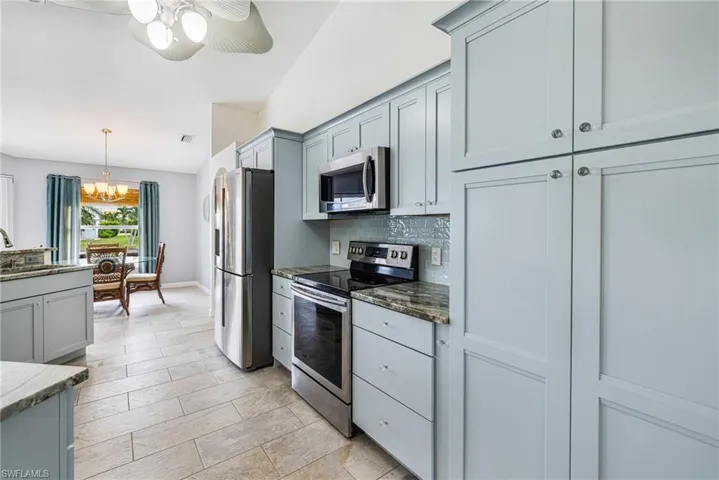 Modern kitchen featuring paneled cabinetry, stainless steel appliances, and stone countertops
