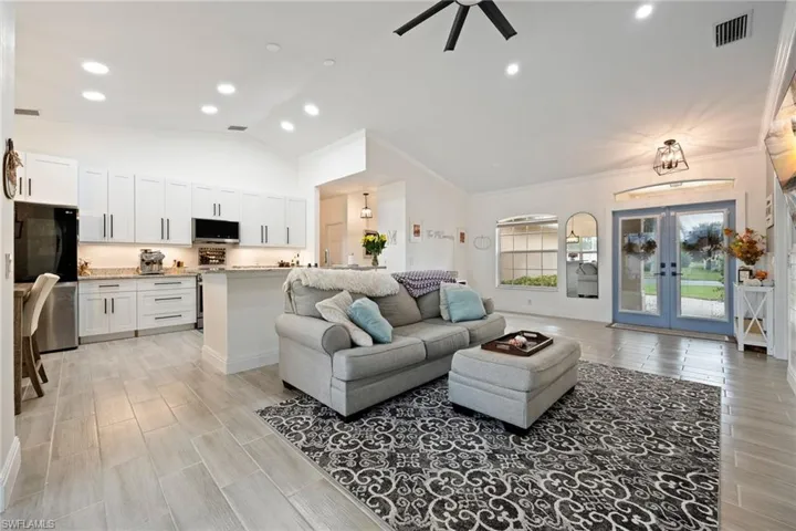 Living room with wood finish floors, french doors, lofted ceiling, recessed lighting, and ornamental molding