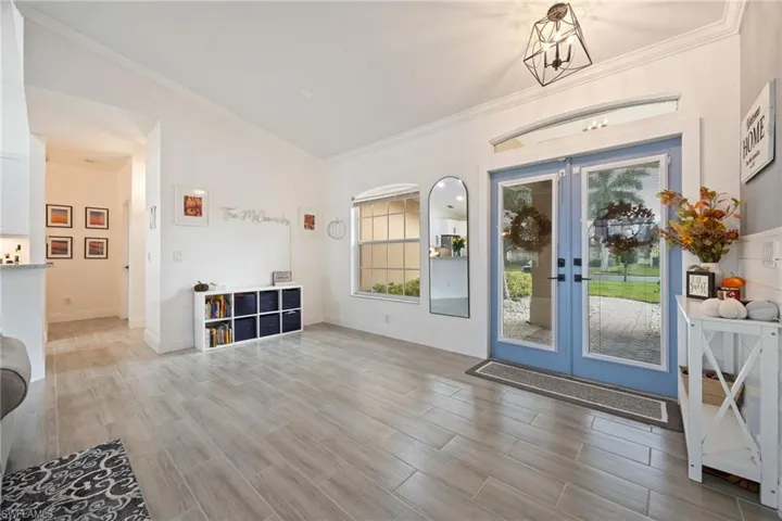 Entryway with wood tiled floors, ornamental molding, french doors, and lofted ceiling
