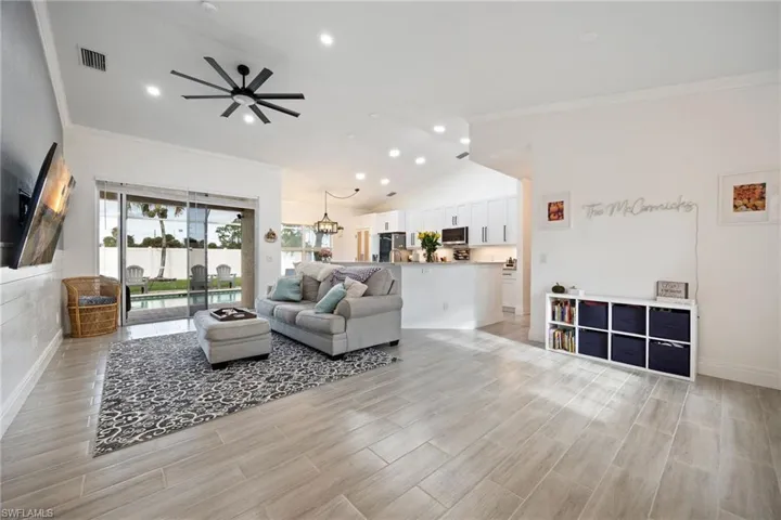 Living room featuring ornamental molding, recessed lighting, wood tiled floors, vaulted ceiling, and a chandelier