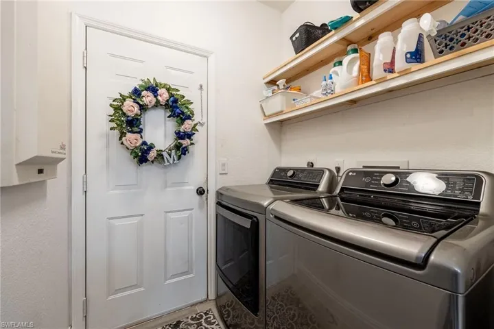 Washroom with washer and clothes dryer and tile patterned floors