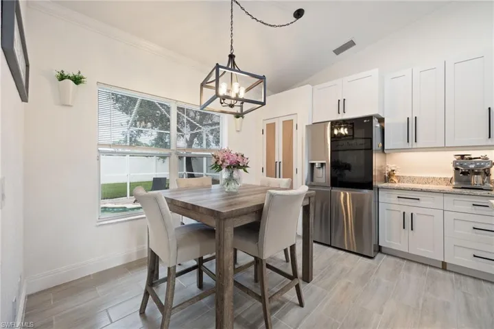 Dining area featuring crown molding, lofted ceiling, wood finish floors, and a chandelier
