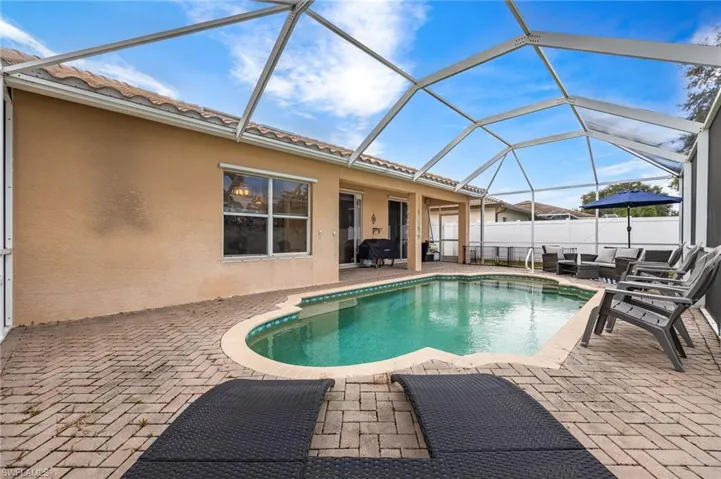 View of pool featuring a sunroom, a patio area, glass enclosure, and an outdoor living space