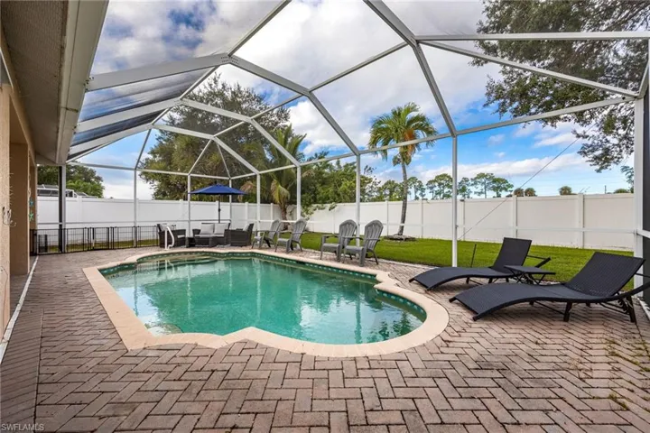 View of pool with glass enclosure, a patio, a sunroom, and a fenced backyard