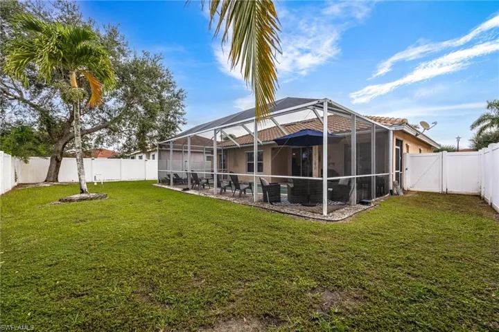 Back of property with a fenced backyard, a lanai, and a sunroom