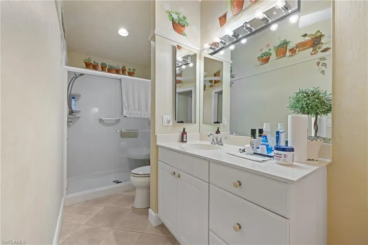 Bathroom featuring vanity, an enclosed shower, tile patterned flooring, and toilet