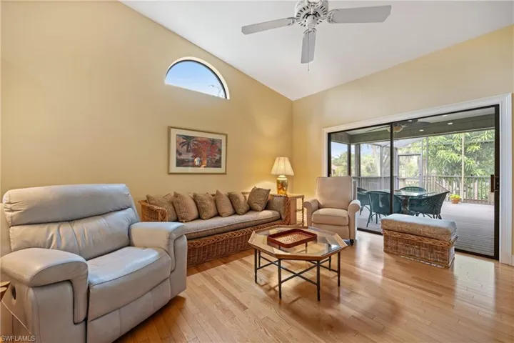 Living room with high vaulted ceiling, ceiling fan, and light wood-type flooring