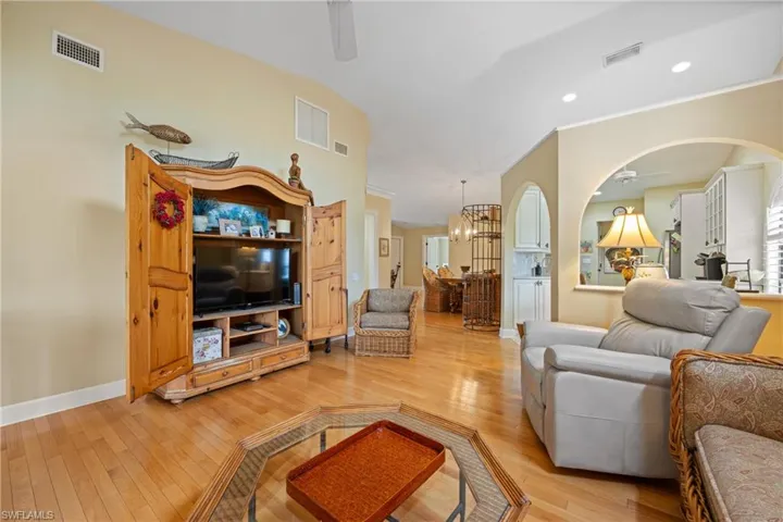 Living room featuring ceiling fan with notable chandelier and light hardwood / wood-style floors