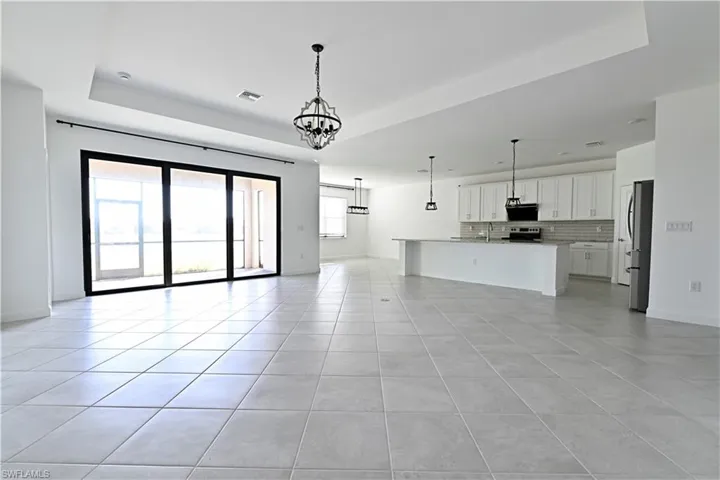 Unfurnished living room featuring a chandelier, a tray ceiling, and light tile patterned flooring