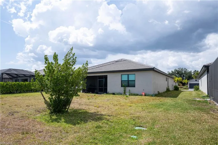 Rear view of property featuring a sunroom, a yard, stucco siding, and glass enclosure