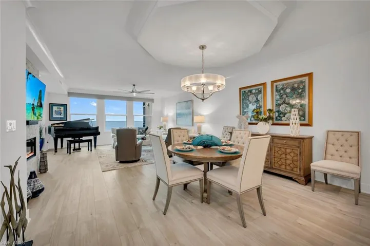 Dining room with a water view, floor to ceiling windows, ceiling fan with notable chandelier, and light hardwood / wood-style flooring