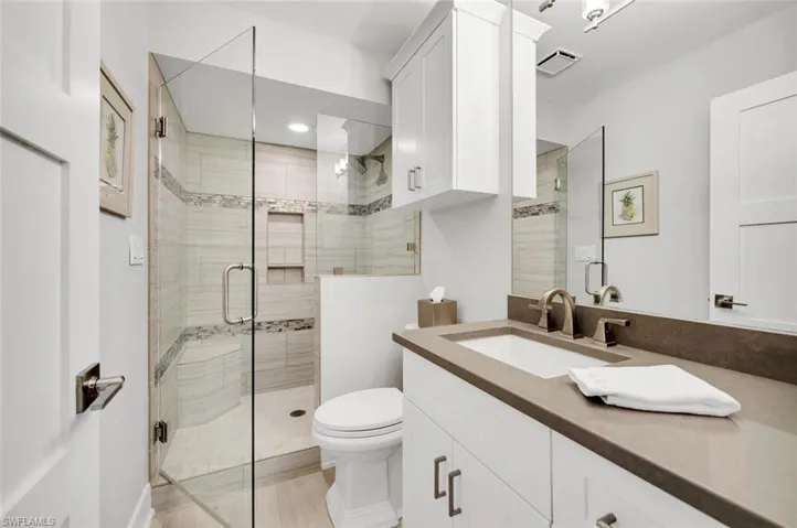 Bathroom with a shower with door, vanity, and toilet