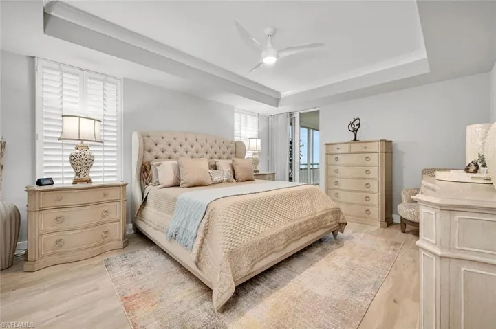 Bedroom with ceiling fan, a raised ceiling, and light hardwood / wood-style floors