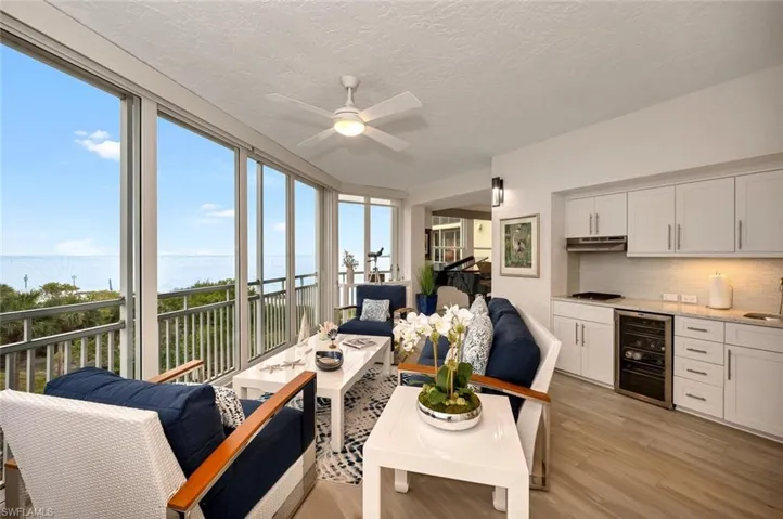 Living room featuring wine cooler, light wood-type flooring, a healthy amount of sunlight, and a water view