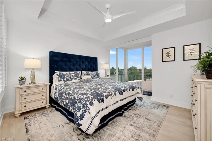 Bedroom featuring a raised ceiling, ornamental molding, light wood-type flooring, and ceiling fan