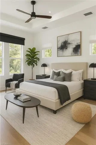 Bedroom with light wood-style flooring, multiple windows, a ceiling fan, recessed lighting, and a raised ceiling