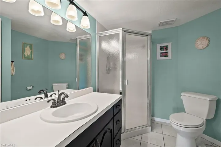 Bathroom featuring tile patterned flooring, vanity, toilet, and an enclosed shower