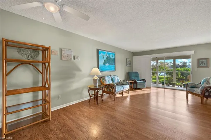 Living area with ceiling fan, a textured ceiling, and hardwood / wood-style flooring