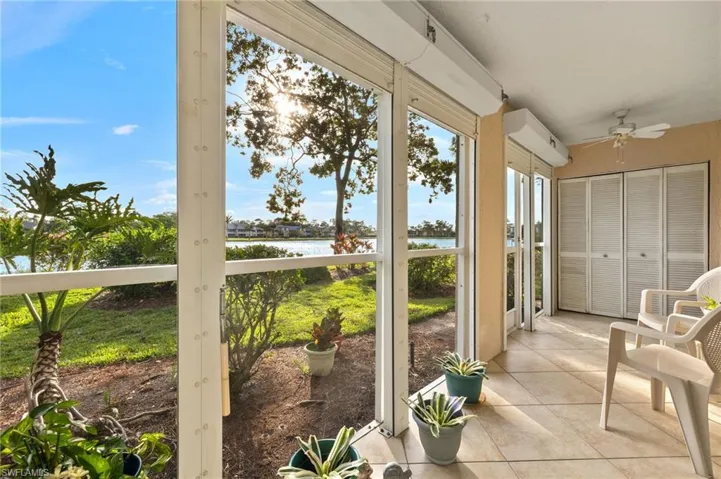 Screened in patio featuring ceiling fans, shutters, and a water view