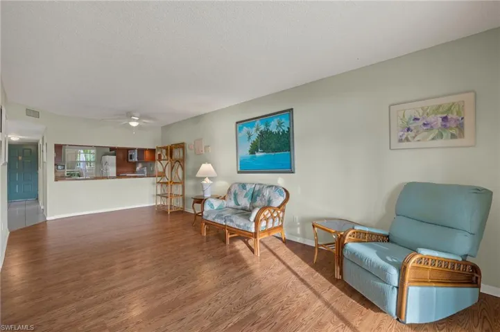 Living area with ceiling fan, wood-type flooring, and a textured ceiling