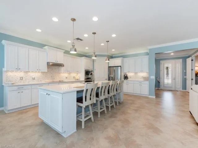 Kitchen with an island with sink, white cabinetry, and stainless steel fridge with ice dispenser