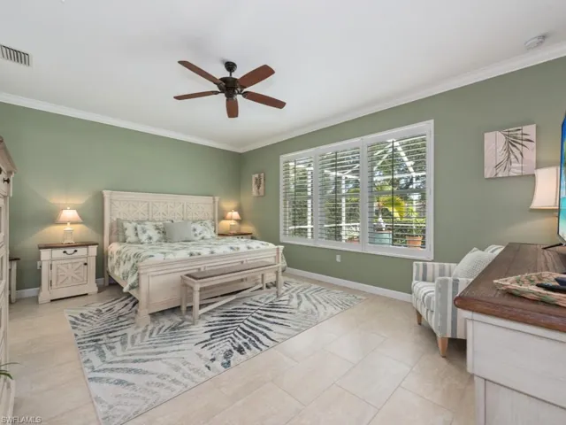 Bedroom featuring ceiling fan, light tile flooring, and ornamental molding
