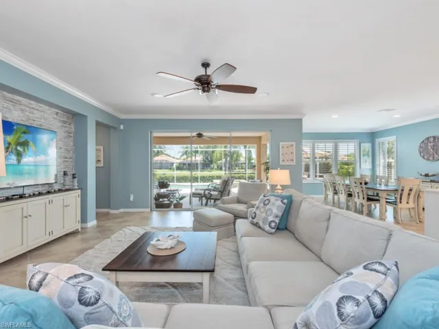 Living room with crown molding, light tile flooring, and ceiling fan