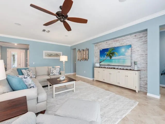 Tiled living room with ornamental molding and ceiling fan