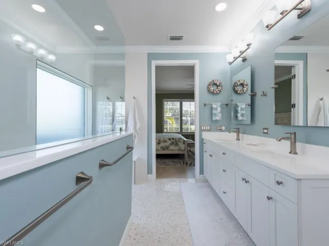 Bathroom with vanity with extensive cabinet space, crown molding, and double sink