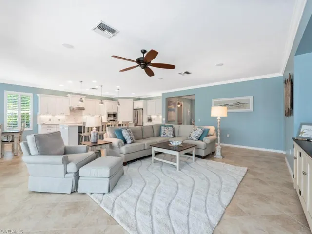 Tiled living room with ceiling fan and crown molding