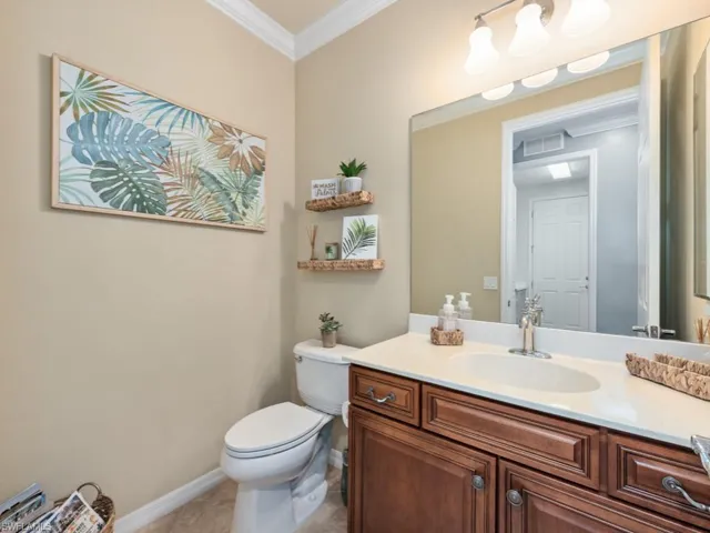 Bathroom with tile floors, ornamental molding, vanity, and toilet