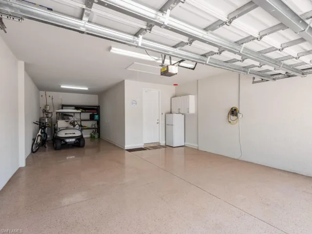 Garage featuring a garage door opener and white fridge